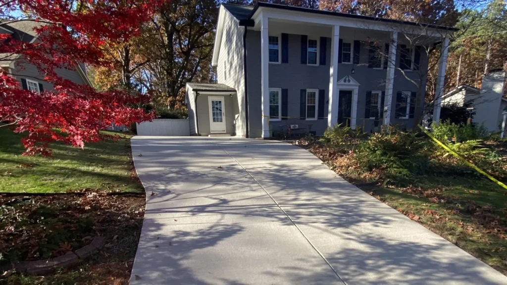 Newly poured concrete driveway for a two-story gray colonial home in Raleigh, North Carolina.