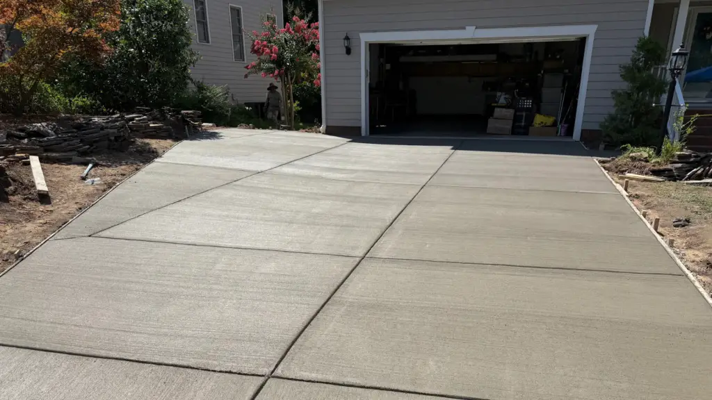 Newly installed concrete driveway in a residential Raleigh setting, showcasing quality craftsmanship and inviting curb appeal