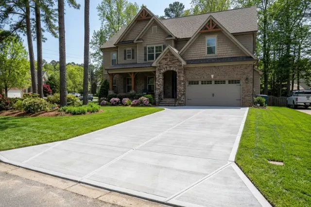 Newly installed concrete driveway in Holly Springs, NC, enhancing the curb appeal of a beautiful home