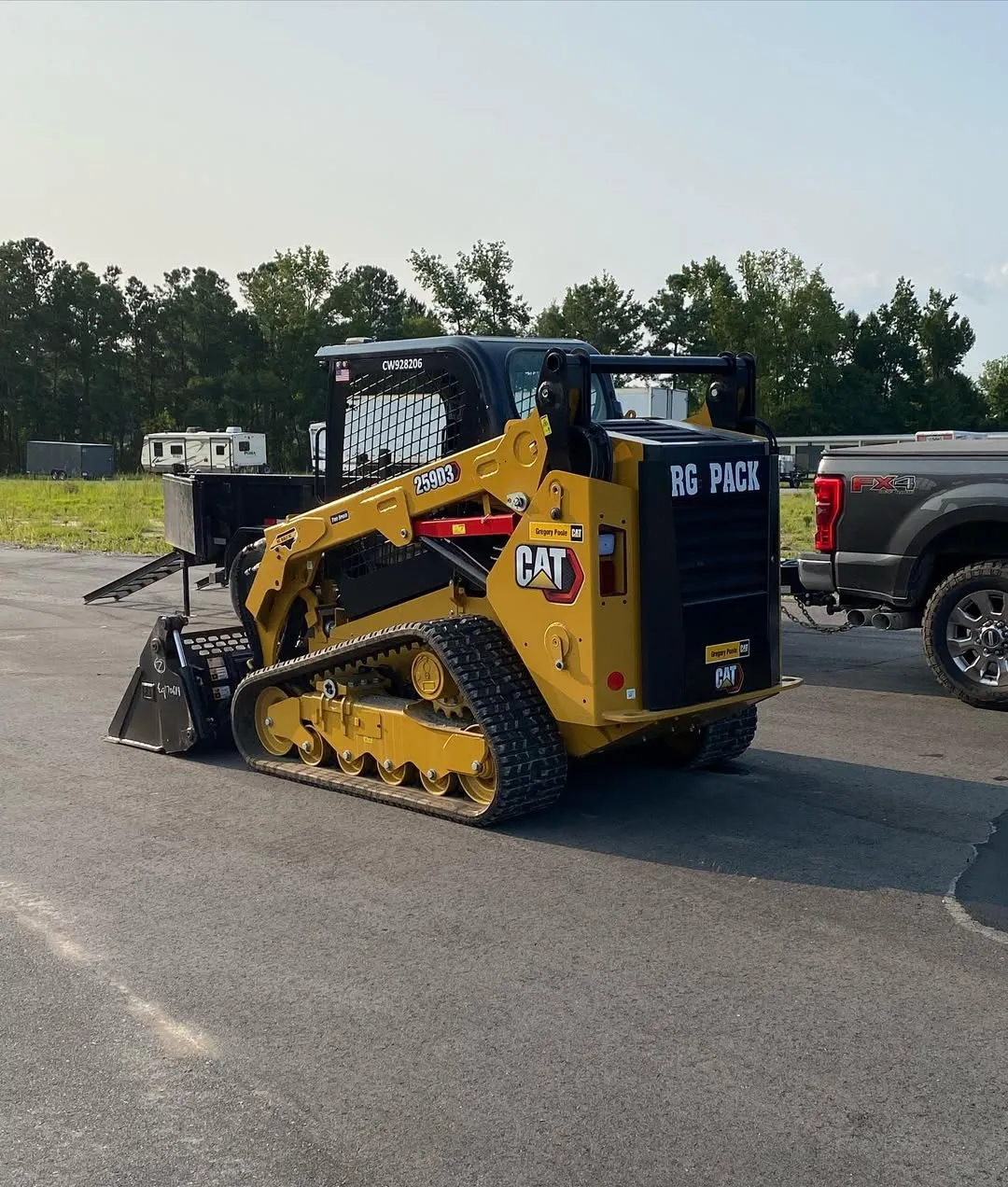 Caterpillar skid steer loader with "RG Pack" branding prepares a concrete driveway base in Raleigh, NC