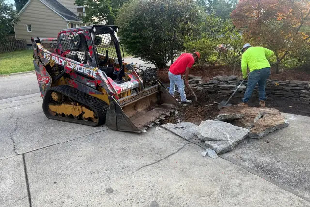 Driveway replacement in Cary, NC, with workers removing damaged concrete